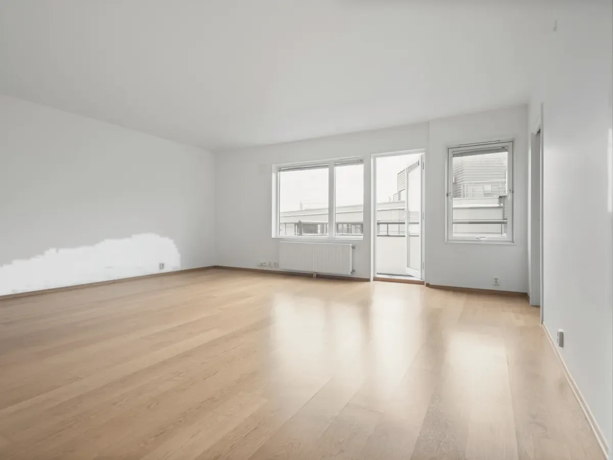 An empty apartment with fresh white walls, oak floors and tall windows